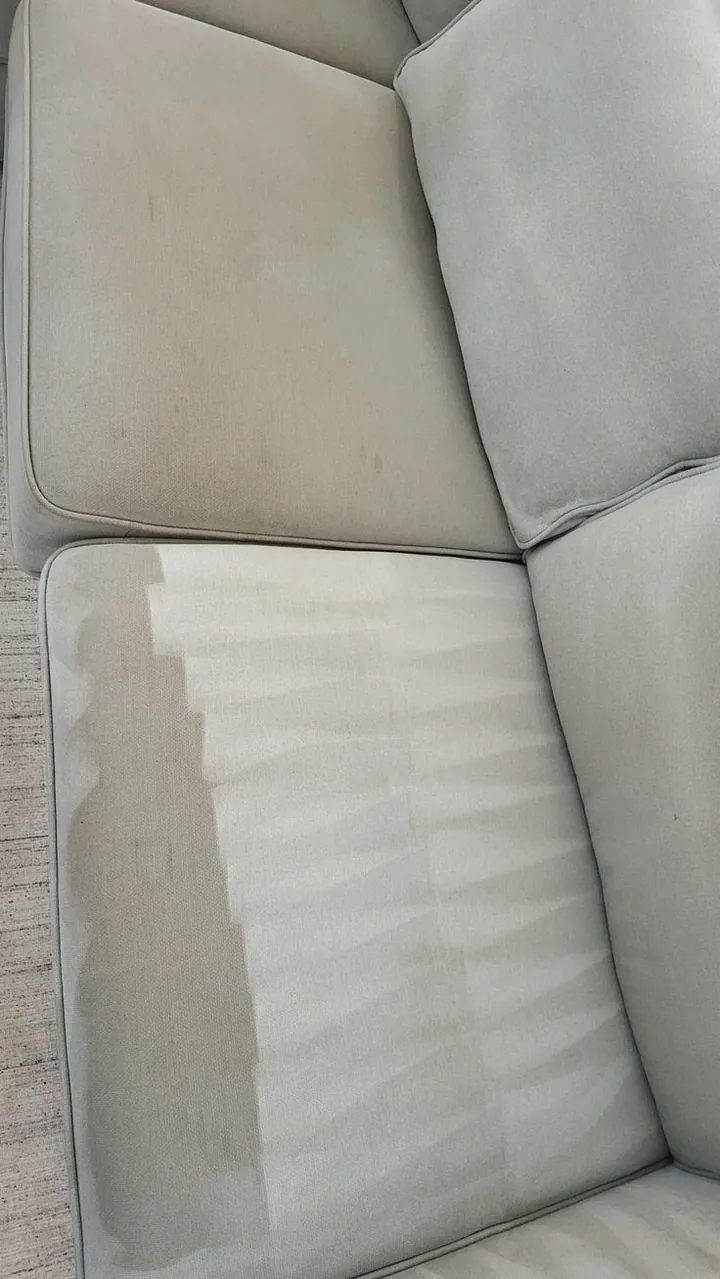 Light gray sofa cushion with one clean half next to the soiled half